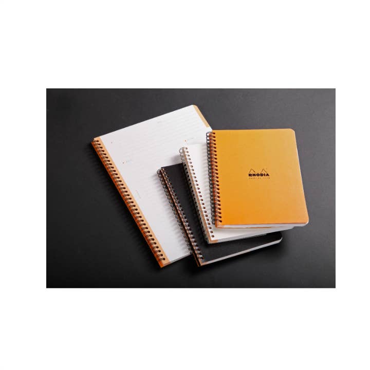 Stack of notebooks with different colored covers on a dark surface