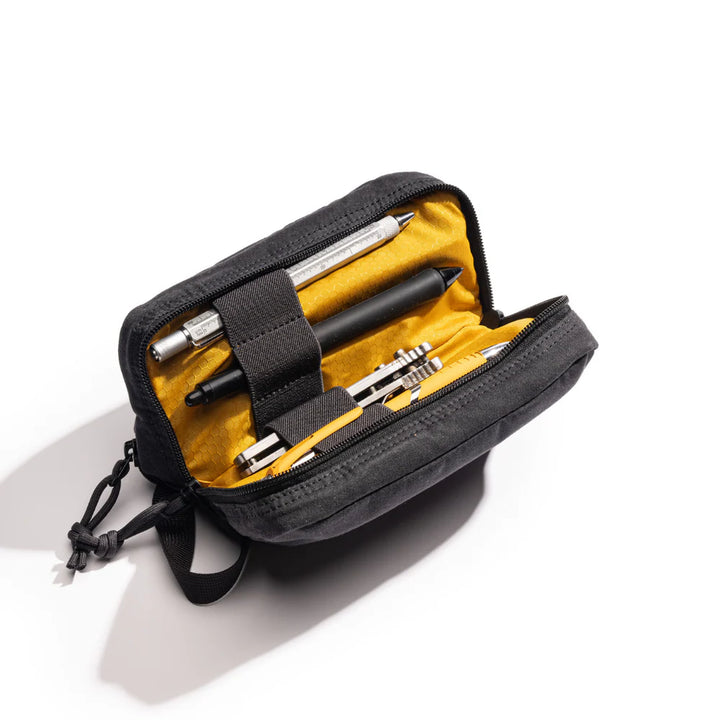 Black pouch with yellow interior containing various tools on a white background