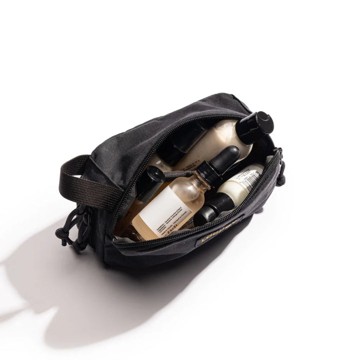 Black toiletry bag with skincare products on a white background