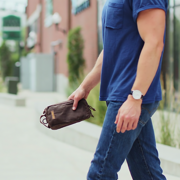 Person holding a brown pouch on a city street
