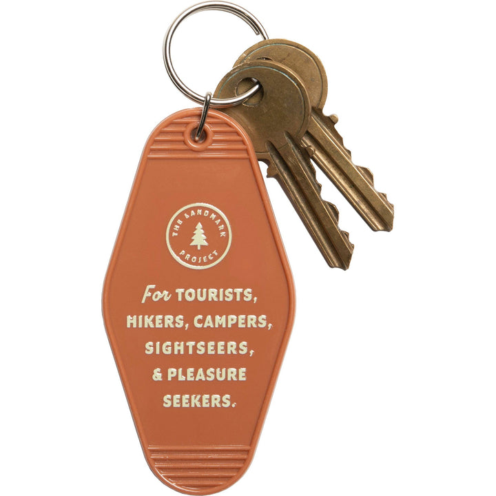 Keychain with keys attached to a brown tag featuring text and a logo on a white background