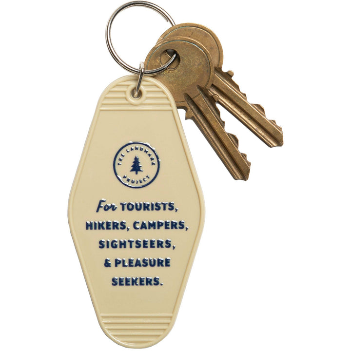 Keychain with keys attached to a beige tag featuring text and a logo on a white background
