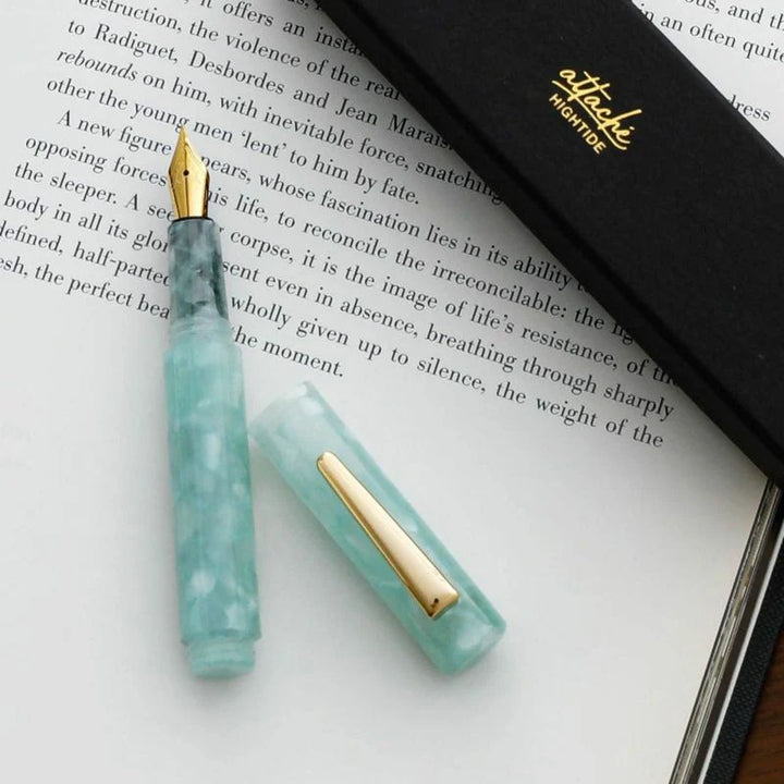 Mint fountain pen with gold accents on an open book