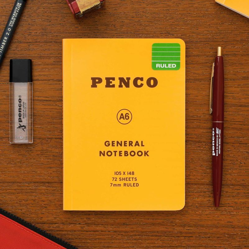 Yellow Penco notebook with a pen and eraser on a wooden surface