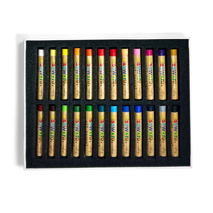 Set of colored oil pastels in a black box on a white background