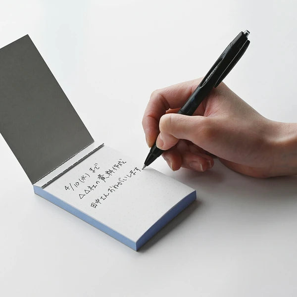 Hand writing on a small notepad with a pen against a white background