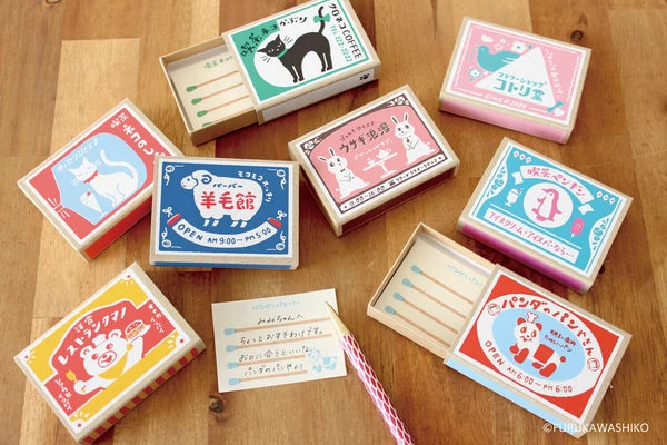 Collection of small matchboxes with colorful designs on a wooden surface