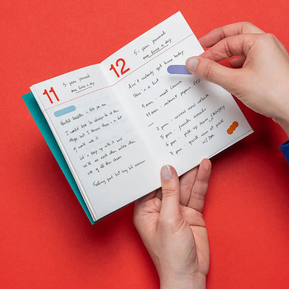 Hands holding a book with a page showing numbers 11 and 12 on a red background