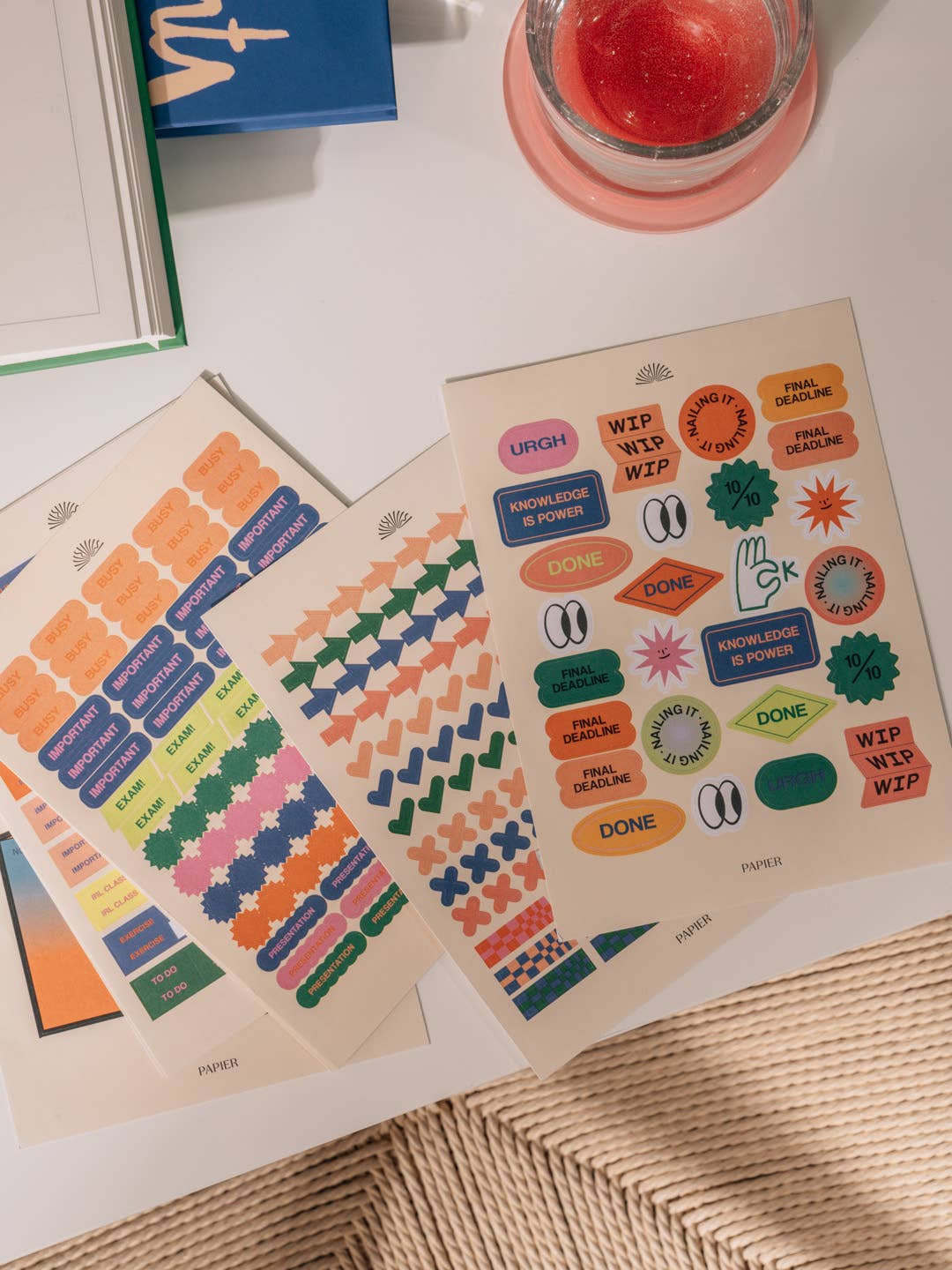 Two sheets of colorful stickers on a textured surface with a candle in the background.