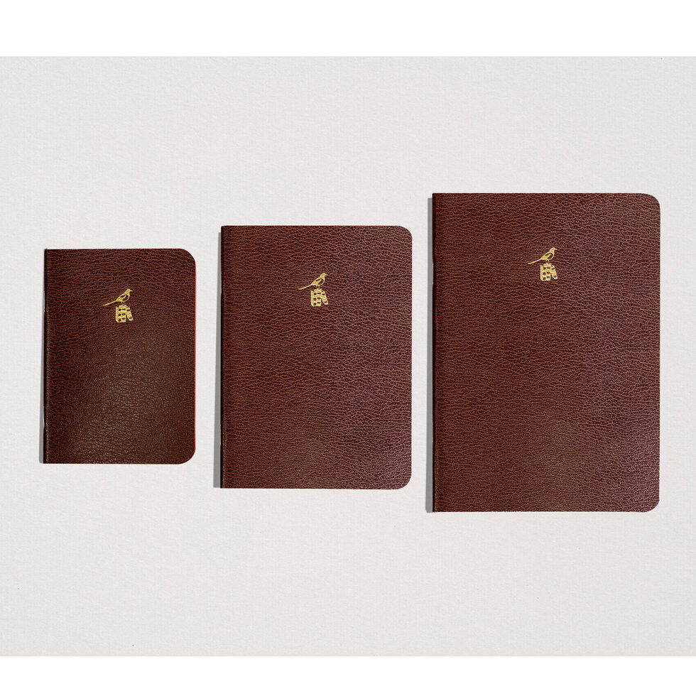 Three brown leather notebooks of different sizes on a white background