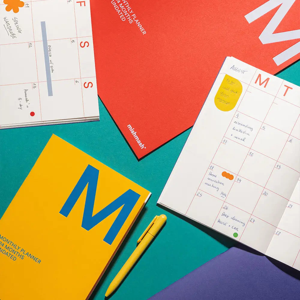 Colorful planners and a pen on a multicolored surface