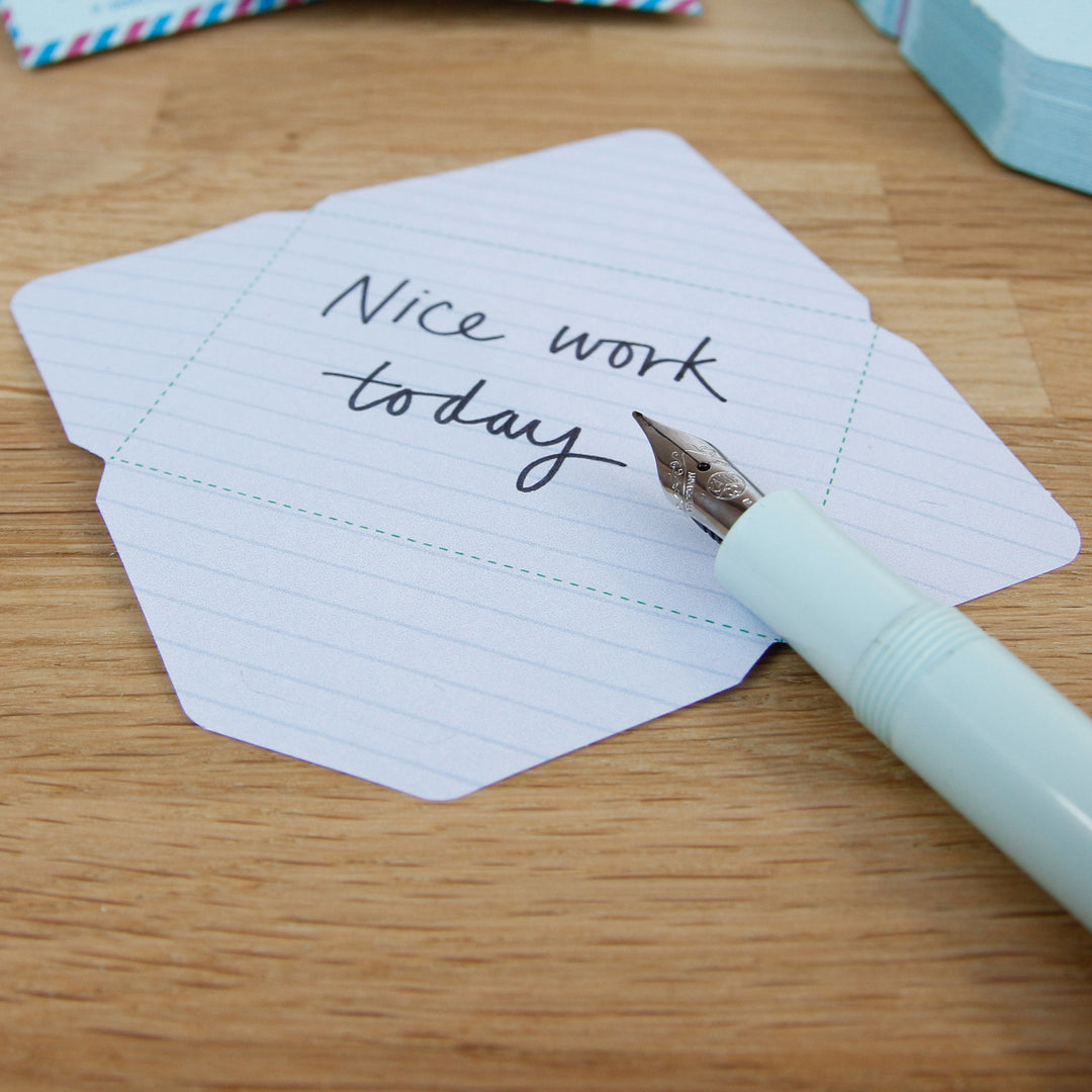 Stack of cards with 'Nice work today' text on a wooden surface with a pen.