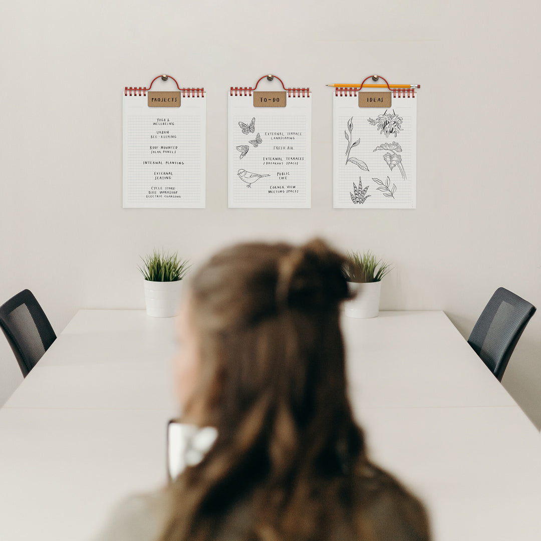 Person sitting at a table with three wall-mounted planners displaying different designs.
