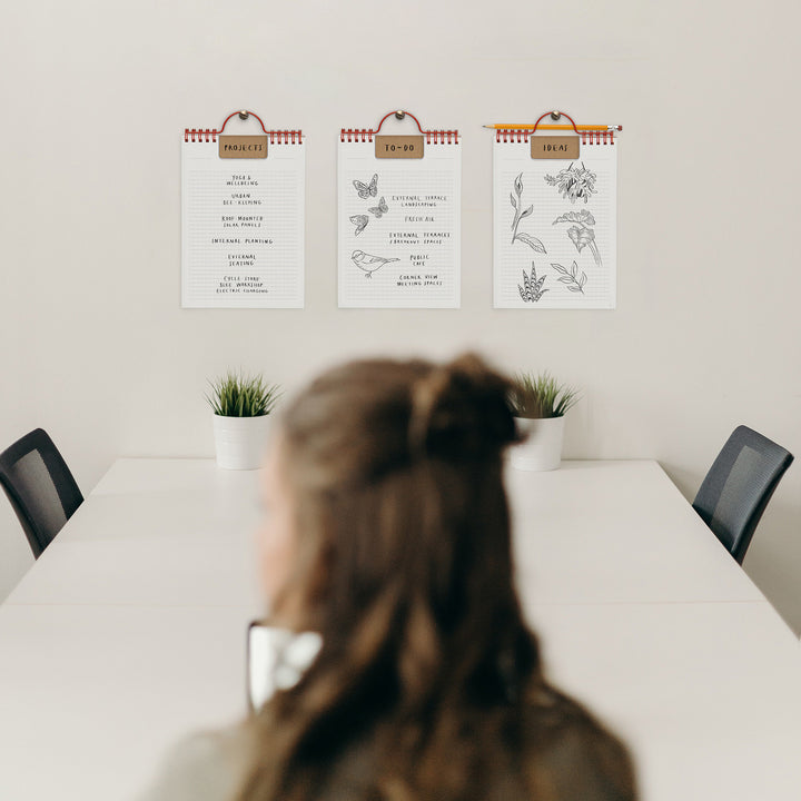 Person sitting at a table with three wall-mounted planners displaying different designs.