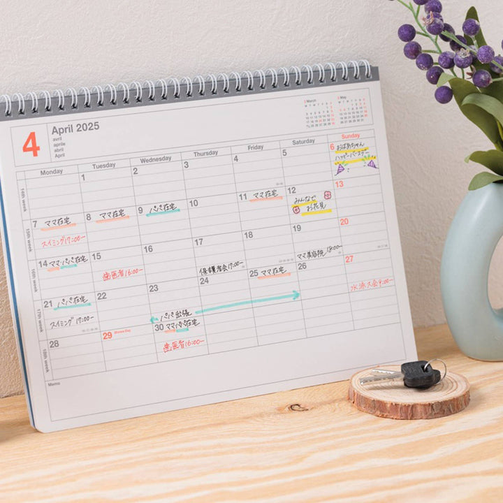 Calendar on a wooden surface with a vase of flowers in the background