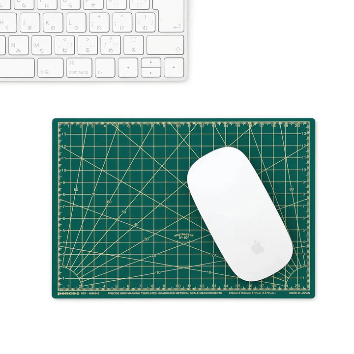 Green grid-patterned mouse pad with a white mouse on a white surface.