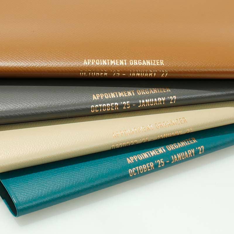 Stack of appointment organizers in different colors with visible text on a white background