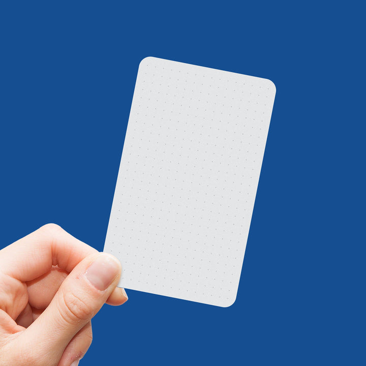 Hand holding a small white card against a blue background