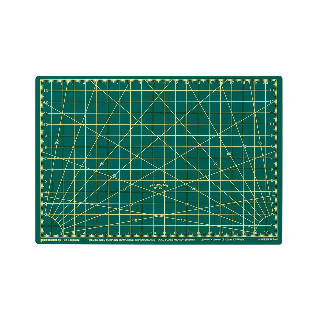 Green cutting mat with grid lines and measurements on a white background