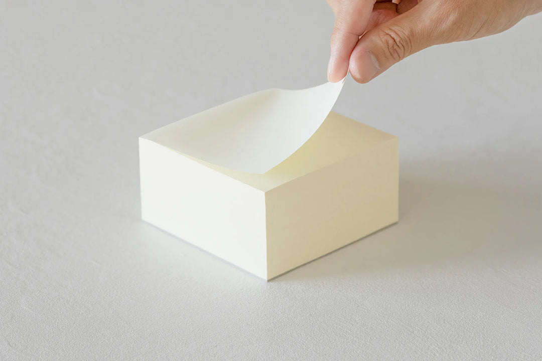 Hand pulling a sheet of paper from a white box on a gray background